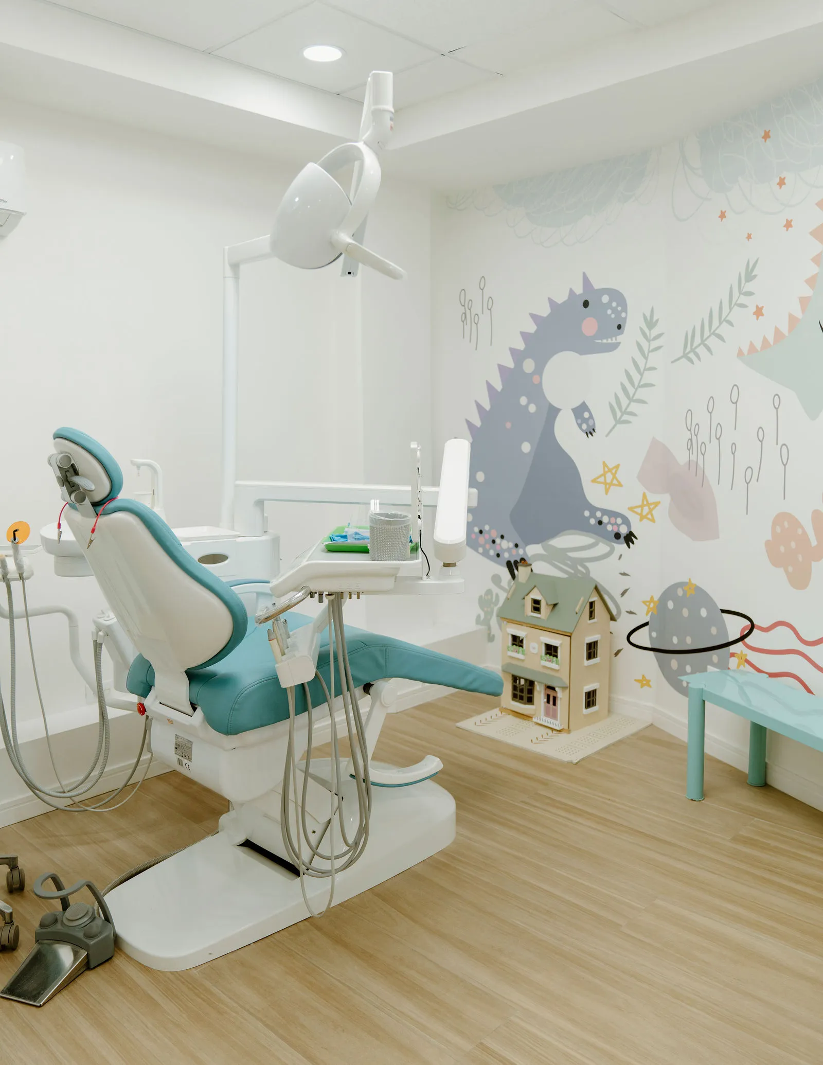 Consultorio de ¡École CUA!: sillón dental color menta y un mural de dinosaurio